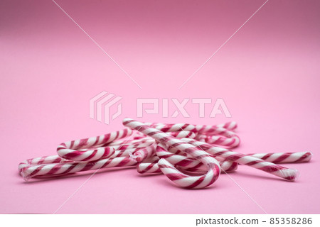 Closeup of red and white stripped candy cane on pink background 85358286