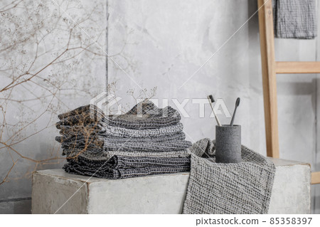 Organic waffle linen towels, bamboo toothbrushes, bathroom zero waste accessories in grey shades in contemporary bathroom interior. Daily body care, spa and wellness zero waste bathroom concept 85358397