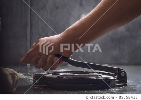 Preparing Dough for Mexican corn tortillas for tacos with tortilla press on grey table top. Closing the press 85358413