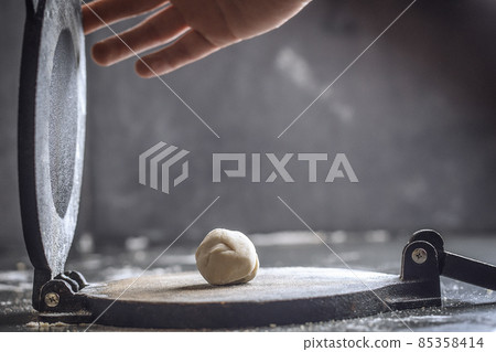 Preparing Dough for Mexican corn tortillas for tacos with tortilla press on grey table top. Closing the press 85358414
