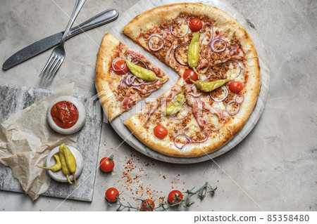 Tasty pizza with ham, mozzarella, minced meat on marble round tray. Garnished on grey stone backdrop with pizza ingredients Tasty pizza with ham, mozzarella, minced meat on marble round tray. Garnished on grey stone backdrop with pizza ingredients 85358480