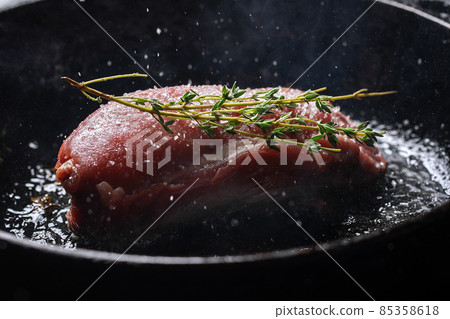 Raw fresh beef steak with seasonings, garlic and rosemary on cast iron frying pan 85358618