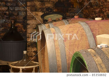 Old cellar with demijohns and wooden barrels. Making wine traditionally Old cellar with demijohns and wooden barrels. Making wine traditionally 85358692