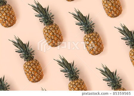 A bright pattern of many pineapples on a trendy soft beige pink background. Tropical ripe juicy fruit flat lay for your design projects 85359565