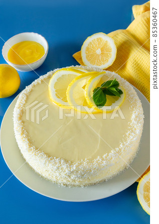 Lemon cake with coconut flakes on a blue background. Delicate dessert with cream. 85360467