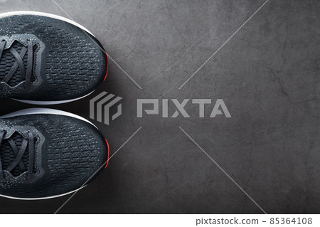 Black running shoes with mesh and black laces close-up on a dark background Black running shoes with mesh and black laces close-up on a dark background 85364108