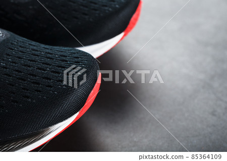 Black running shoes with mesh and black laces close-up on a dark background Black running shoes with mesh and black laces close-up on a dark background 85364109