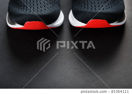 Black running shoes with mesh and black laces close-up on a dark background Black running shoes with mesh and black laces close-up on a dark background 85364111