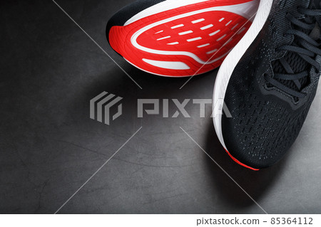 Black running shoes with mesh and black laces close-up on a dark background Black running shoes with mesh and black laces close-up on a dark background 85364112