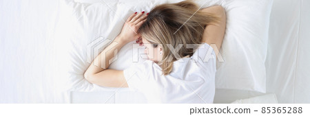 Young woman sleeping on her stomach in white bed top view Young woman sleeping on her stomach in white bed top view 85365288