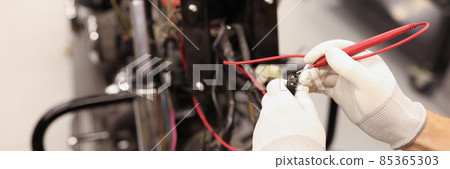 Male repairman checking electrics of motorcycle using tester closeup 85365303