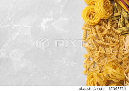 Different types of pasta on light grey marble table, flat lay. Space for text 85367714