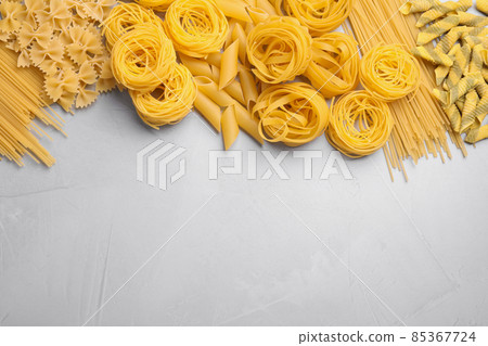 Different types of pasta on light grey table, flat lay. Space for text 85367724