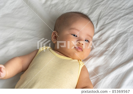 Adorable Asian baby girl on the white bed background Adorable Asian baby girl on the white bed background 85369567