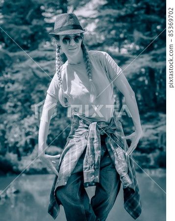 A girl with pigtails and casual outfit stands in a hiphop pose in the park. Street dancer. Monochrome photography A girl with pigtails and casual outfit stands in a hiphop pose in the park. Street dancer. Monochrome photography 85369702