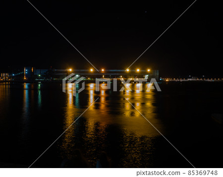 Night seascape with a large metal structure on the pier illuminated by bright lights Night seascape with a large metal structure on the pier illuminated by bright lights 85369748