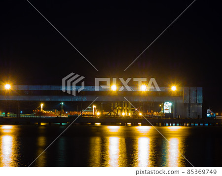 Night view of a seaport with a metal structure illuminated by bright lights Night view of a seaport with a metal structure illuminated by bright lights 85369749