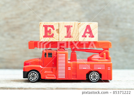 Fire ladder truck hold letter block in word EIA (abbreviation of Environmental Impact Assessment) on wood background 85371222