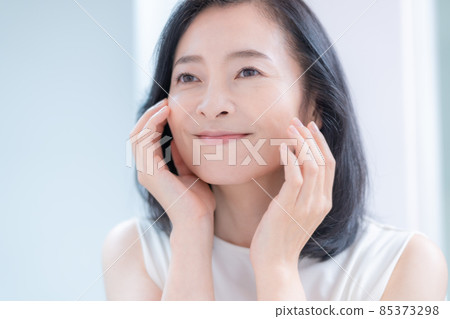 撫摸鏡子中映出的肌膚而微笑的中年婦女 撫摸鏡子中映出的肌膚而微笑的中年婦女 85373298