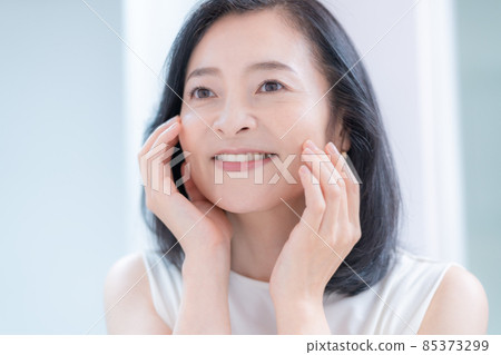 撫摸鏡子中映出的肌膚而微笑的中年婦女 撫摸鏡子中映出的肌膚而微笑的中年婦女 85373299