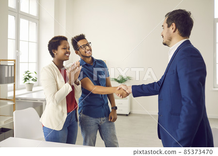 Real estate agent shake hand of excited couple congratulate with home purchase or buy. Realtor or broker handshake buyers or clients greeting with house ownership. Rental, realty concept. Real estate agent shake hand of excited couple congratulate with home purchase or buy. Realtor or broker handshake buyers or clients greeting with house ownership. Rental, realty concept. 85373470