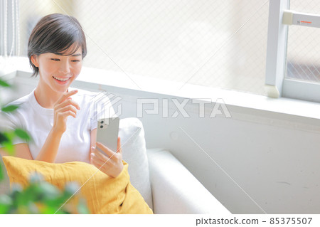 一個女人拿著一個墊子,伸手去拿智能手機 1 一個女人拿著一個墊子,伸手去拿智能手機 1 85375507