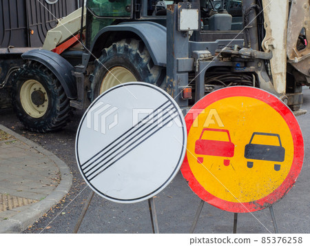 Round road signs stand on the background of the excavator. Repair work on the road Round road signs stand on the background of the excavator. Repair work on the road 85376258