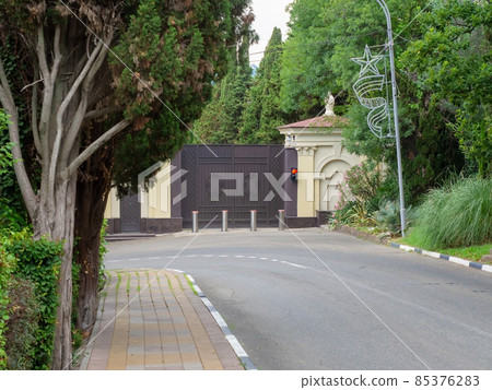Private railway gate with traffic lights and automatic bollards surrounded by green trees located near the road Private railway gate with traffic lights and automatic bollards surrounded by green trees located near the road 85376283