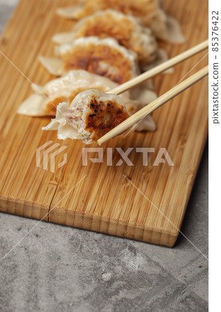 Gyoza or dumplings snack with soy sauce on wood board and grey clay background Gyoza or dumplings snack with soy sauce on wood board and grey clay background 85376422