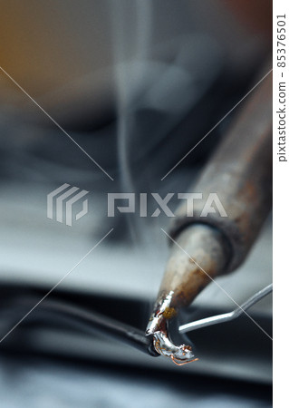 Wires being soldered together with a soldering iron. Melting solder wire on soldering iron tip Wires being soldered together with a soldering iron. Melting solder wire on soldering iron tip 85376501