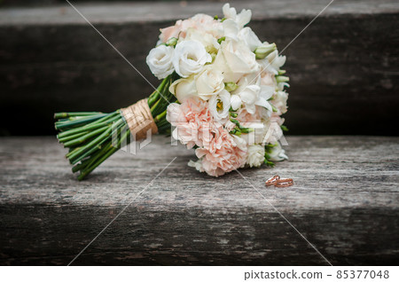 Gold wedding rings and colorfull bouquet of flowers 85377048