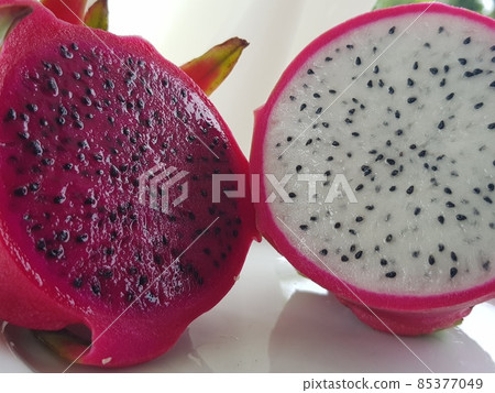 Asian tropical exotic fruit pitahaya cactus red and white, cut in half. Pulp and seeds outside, front view. 85377049