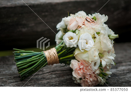 Gold wedding rings and colorfull bouquet of flowers 85377050