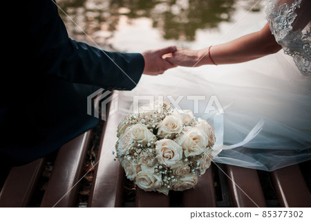 Bouquet of flowers and couple of hands on the table Bouquet of flowers and couple of hands on the table 85377302