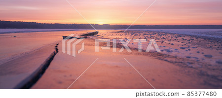 Winter landscape of frozen lake at sunset in warm purple tones. Winter landscape of frozen lake at sunset in warm purple tones. 85377480