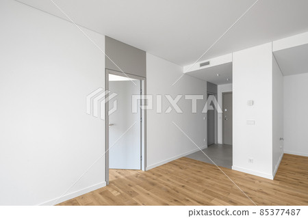 Empty minimalist modern room with white walls, opened grey door, grey floor tiles and oak wood floor Empty minimalist modern room with white walls, opened grey door, grey floor tiles and oak wood floor 85377487