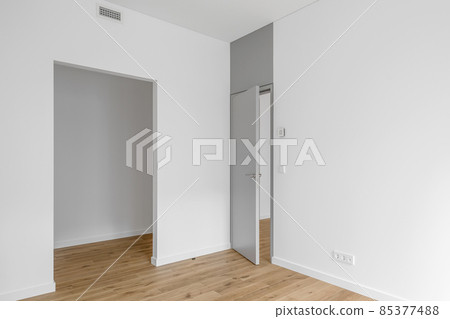 Empty minimalist modern room with white walls, opened grey door and oak wood floor Empty minimalist modern room with white walls, opened grey door and oak wood floor 85377488