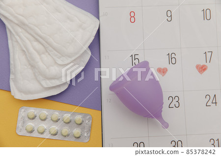 Calendar, sanitary pads and menstrual cup with pain relief pills close-up. Woman critical days concept Calendar, sanitary pads and menstrual cup with pain relief pills close-up. Woman critical days concept 85378242