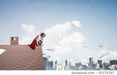 Girl power concept with cute kid guardian against cityscape background. Mixed media Girl power concept with cute kid guardian against cityscape background. Mixed media 85378397