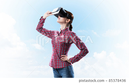 Girl in checked shirt wearing VR glasses experiencing another reality 85378436