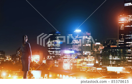Woman looking at night city Woman looking at night city 85378615