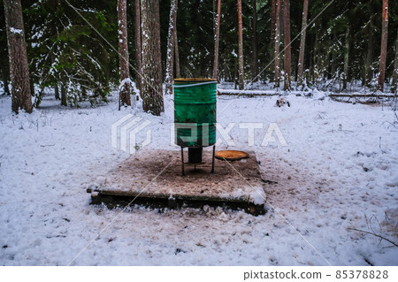 Manger for winter feeding of wild animals in forest. Forest animal feeder in winter. Defocused 85378828