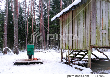 Manger for winter feeding of wild animals in forest. Forest animal feeder in winter. Defocused 85378829