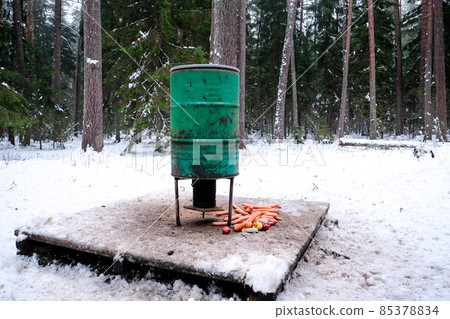Manger for winter feeding of wild animals in forest. Forest animal feeder in winter. Defocused Manger for winter feeding of wild animals in forest. Forest animal feeder in winter. Defocused 85378834