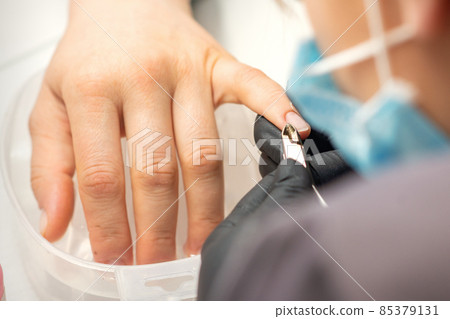 Nail master removing nails cuticle with a nipper, manicure hygiene in a beauty salon. 85379131