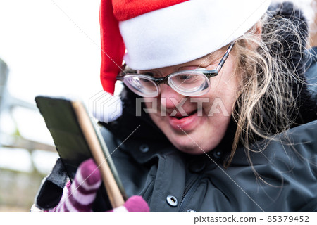 Outdoor portrait of a39 year old white woman with Down Syndrome, having a video call with her family 85379452