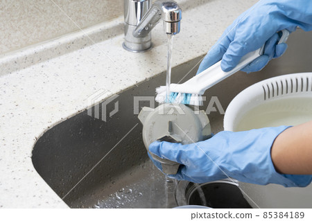 Hands of a male house cleaning worker who brushes the drain trap Hands of a male house cleaning worker who brushes the drain trap 85384189