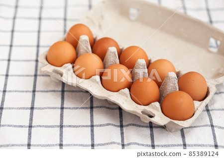 A few brown eggs among the cells of a large cardboard bag, a chicken egg as a valuable nutritious product, a tray for carrying and storing fragile eggs. A full package of eggs, an important food item A few brown eggs among the cells of a large cardboard bag, a chicken egg as a valuable nutritious product, a tray for carrying and storing fragile eggs. A full package of eggs, an important food item 85389124