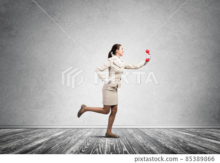 Woman running in room with vintage red phone 85389866