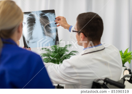 A doctor and nurse look at a photograph of a patient's lungs. 85390319